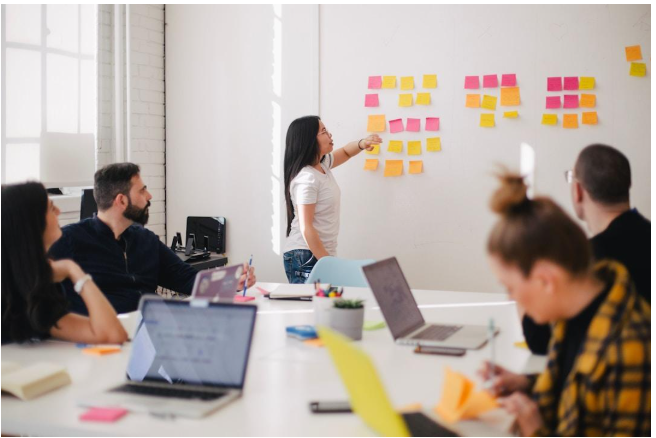 A woman writes on sticky notes attached to a whiteboard, focusing on account planning tools and strategies.