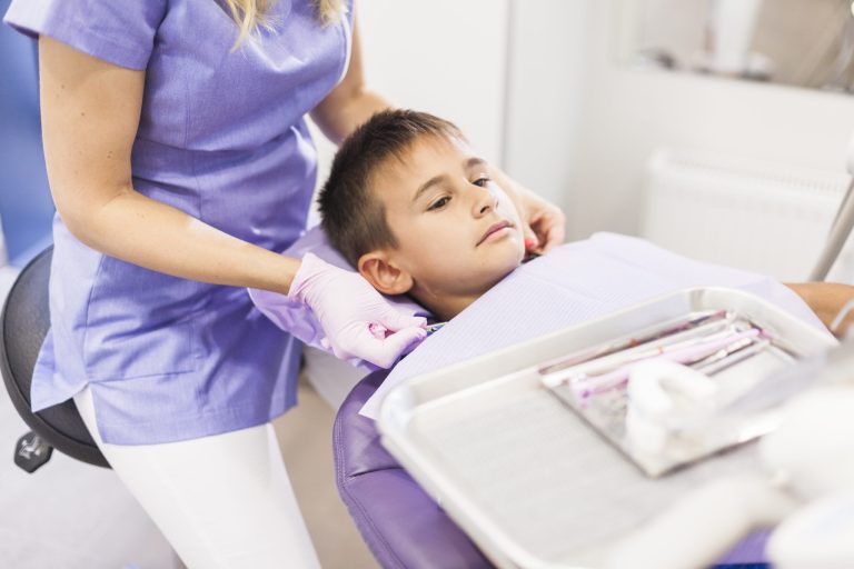 dentist sitting near boy leaning dental chair clinic scaled 1 What Every Parent in Surrey Should Know About Early Orthodontics
