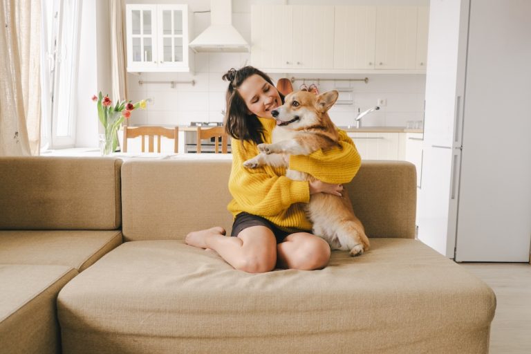 YoungWomanWithCorgiOnSofa Pet-Friendly Apartment Living With Modern Comfort Features
