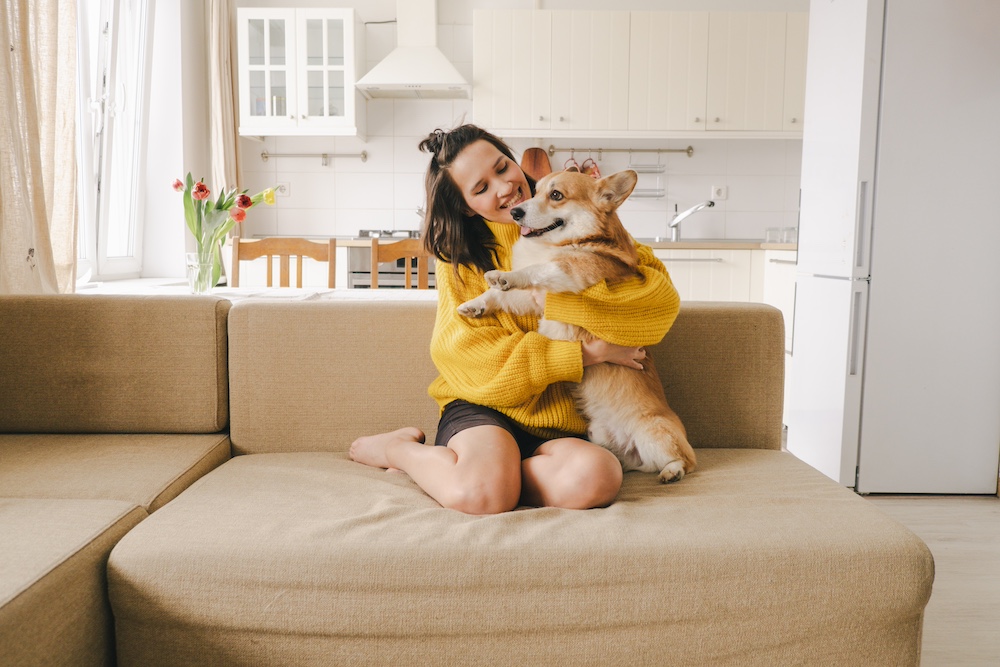 YoungWomanWithCorgiOnSofa Pet-Friendly Apartment Living With Modern Comfort Features